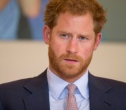 A photo shows Prince Harry wearing a grey suit, white shirt and red and white tie