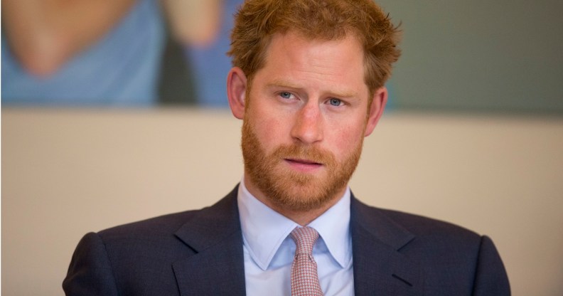 A photo shows Prince Harry wearing a grey suit, white shirt and red and white tie