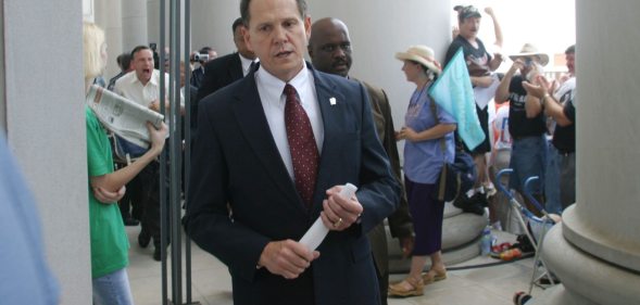 MONTGOMERY, AL ? AUGUST 21: Alabama Supreme Court Chief Justice Roy Moore walks back into the state Judicial Building after addressing supporters August 21, 2003 in Montgomery, Alabama. The eight other justices today overruled Moore?s defiance of a federal court order to remove a 5,300 lb granite monument of the Ten Commandments that is exhibited in the Judicial Building. Moore defied a deadline to get rid of the monument by midnight today. The U.S. Supreme Court declined to consider the issue Wednesday. (Photo by Gary Tramontina/Getty Images)