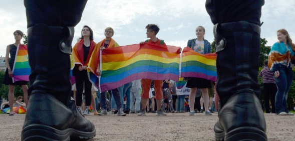 People wave rainbow flags during a pride rally in Saint Petersburg, on Agust 12, 2017 as police look on.