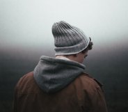 A man wearing a beanie hat and hoody looking away from the camera