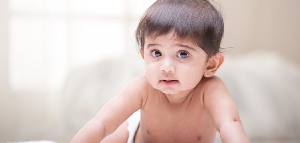 A baby crawling on a blanket. (Creative Commons)