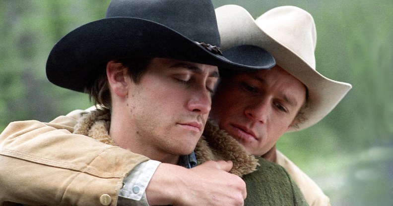 A still from the 2005 film Brokeback Mountain showing actors Jake Gyllenhaal and Heath Ledger dressed in their cowboy outfits with Ledger standing close to Gyllenhaal with his arm around him