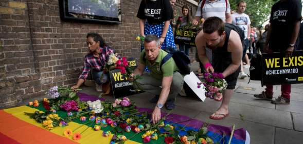 Demonstrators lay roses on a rainbow flag as they protest over an alleged crackdown on gay men in Chechnya