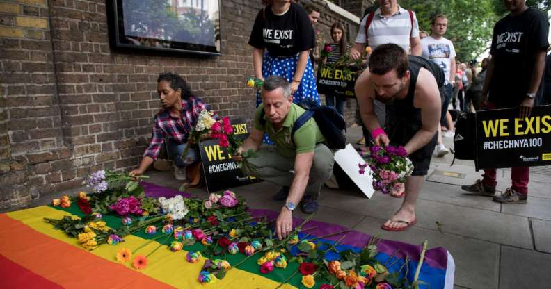 Demonstrators lay roses on a rainbow flag as they protest over an alleged crackdown on gay men in Chechnya