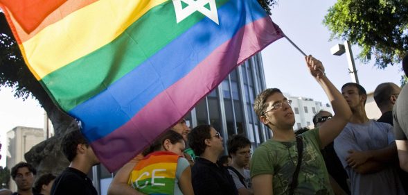 An Israeli man waves a Pride rainbow flag bearing the Star of David