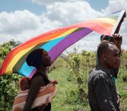 Two LGBT+ refugees and a child march holding a rainbow flag