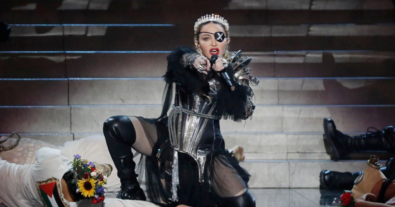 Madonna kneeling on stage wearing her Madame X eyepatch