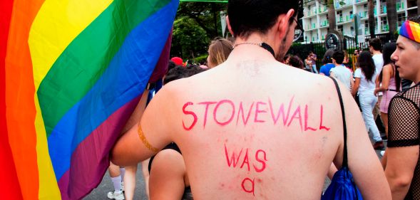 A topless man with 'Stonewall was a riot' written on his back