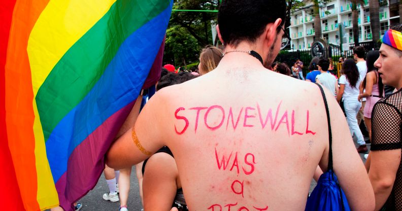 A topless man with 'Stonewall was a riot' written on his back