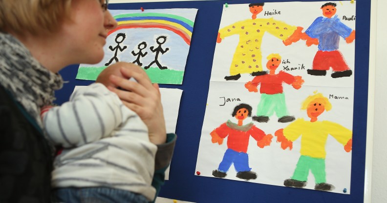A woman holding a baby looking at drawings. She is at Germany's first gay parent counselling centre.