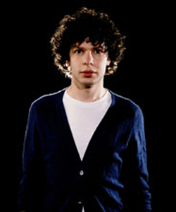 Simon Amstell facing the camera wearing a navy blue cardigan