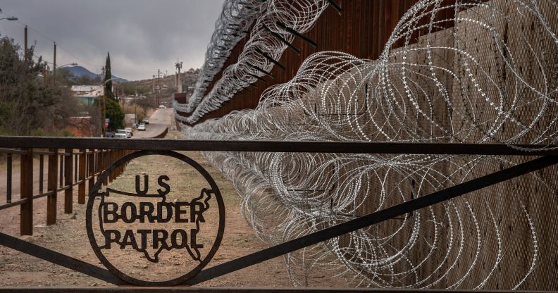 A metal fence marked with the US Border Patrol sign prevents people to get close to the barbed wire covering the US/Mexico border fence