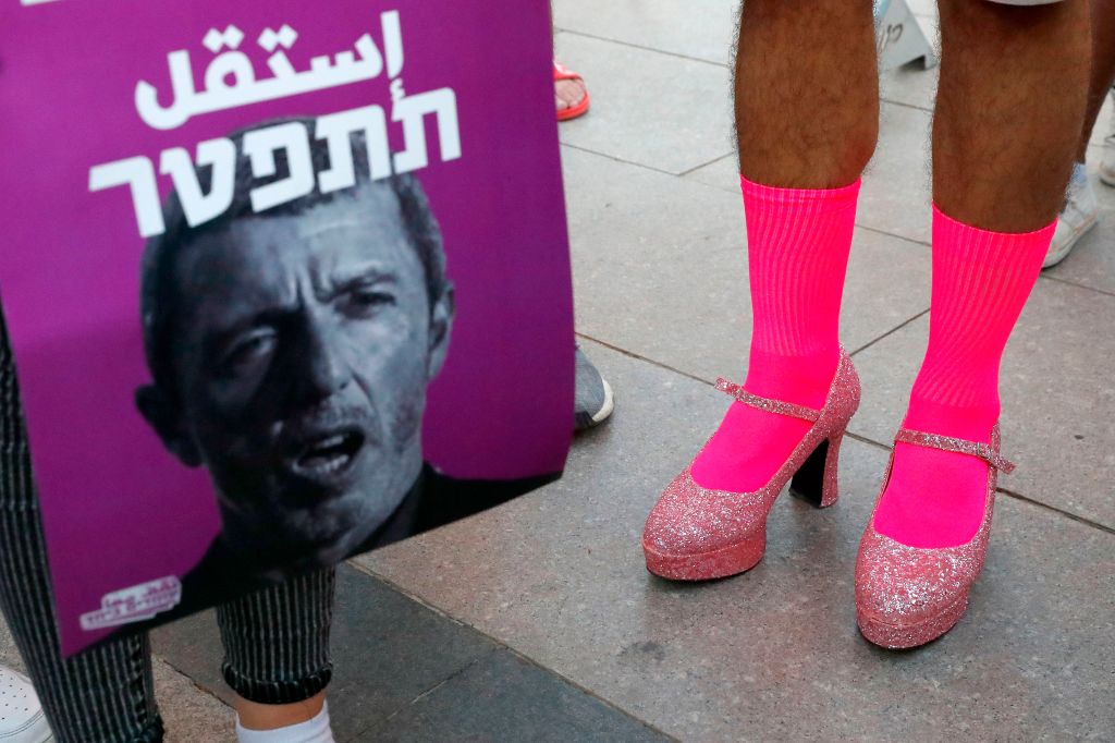 Members of the LGBT community hold a banner reading in Hebrew 'A homophobic Racist Has to Quit' during a rally against Israel's Education Minister Rafi Peretz following his remarks on gay conversion therapy, in the Israeli coastal city of Tel Aviv on July 14, 2019.