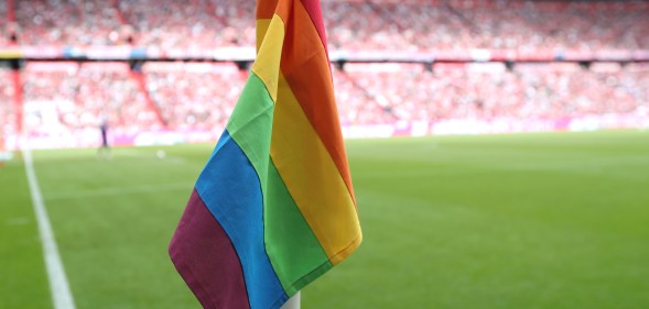 A rainbow corner flag flying on a football pitch