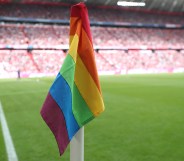 A rainbow corner flag flying on a football pitch