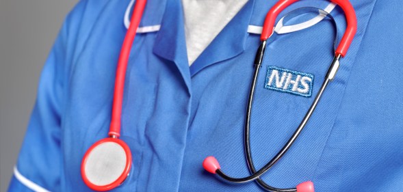 A close-up of somebody wearing an NHS uniform with a stethoscope around their neck.