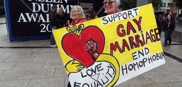 A woman holding a placard which reads: "Support gay marriage end homophobia."