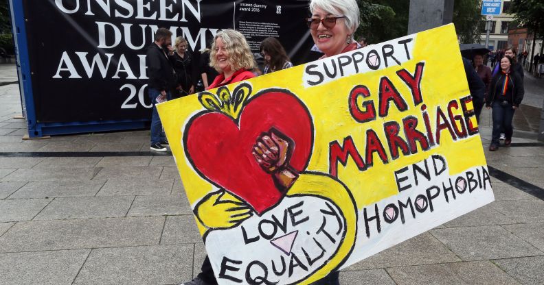 A woman holding a placard which reads: "Support gay marriage end homophobia."