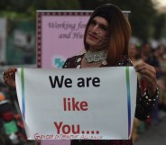 A Pakistani transgender activist holding a sign saying "we are like you."