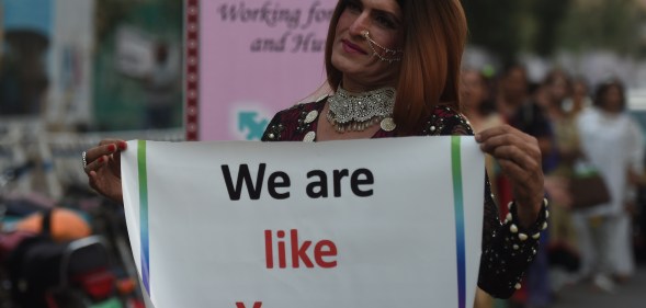 A Pakistani transgender activist holding a sign saying "we are like you."