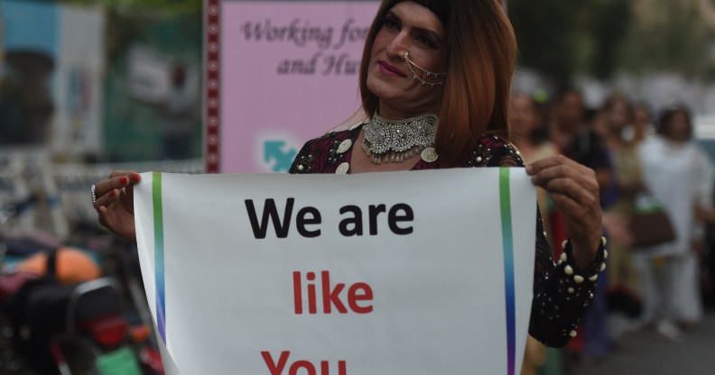 A Pakistani transgender activist holding a sign saying "we are like you."