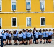 A row of school children in shorts and skirts