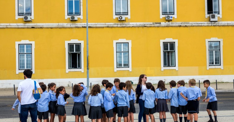 A row of school children in shorts and skirts