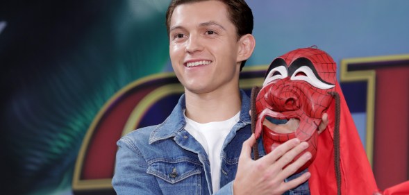 Tom Holland holding a Spider-Man mask