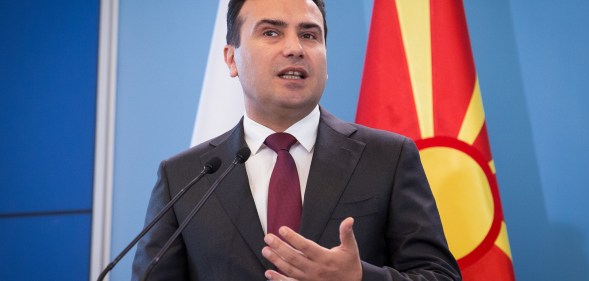 Zoran Zaev speaking in front of a North Macedonia flag.