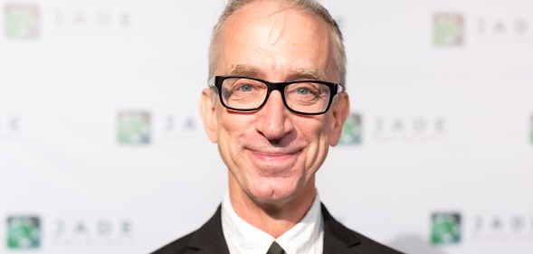 Andy Dick smiling, wearing a suit and black tie