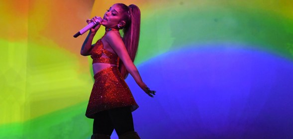 Ariana GRnade singing in front of a rainbow