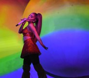 Ariana GRnade singing in front of a rainbow