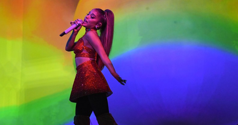 Ariana GRnade singing in front of a rainbow