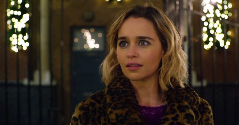 Emilia Clarke looking wide-eyed in a leopard-print coat
