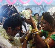 A bride places a garland over her groom's head