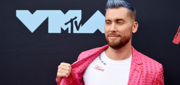 Lance Bass pulling his jacket aside to show the 'Tearin' Up My Heart' message on his t-shirt