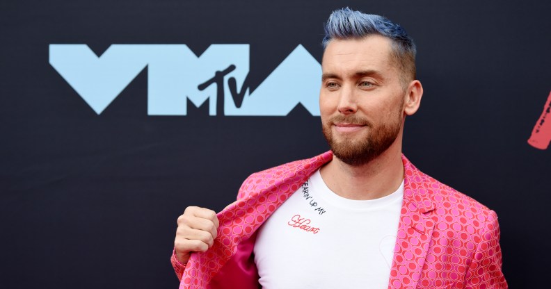 Lance Bass pulling his jacket aside to show the 'Tearin' Up My Heart' message on his t-shirt