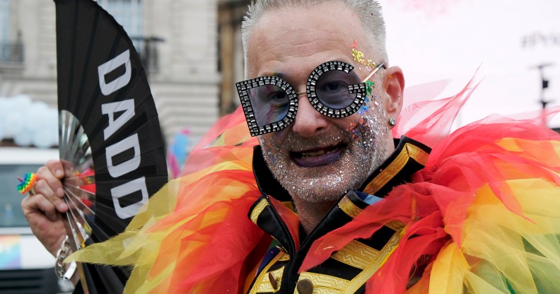 Pride participant seen with rainbow feathers and a "Daddy" fan
