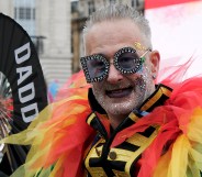 Pride participant seen with rainbow feathers and a "Daddy" fan