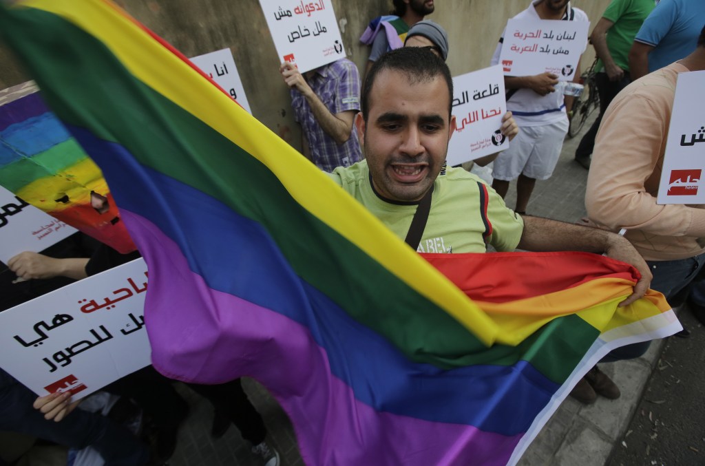 A protester waves the gay pride flag as others hold banners during an anti-homophobia rally in Beirut on April 30, 2013.