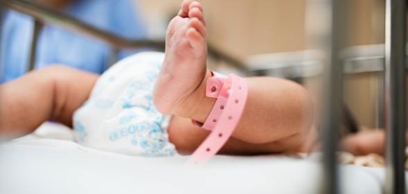 A baby with a pink tag around their ankle