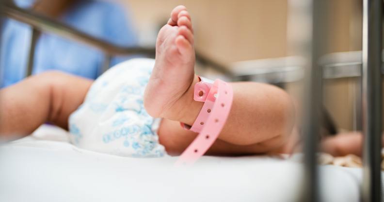 A baby with a pink tag around their ankle