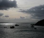 View out to sea from Creux Harbour on Sark, showing fishing boats in silhouette on a grey sea with a cloudy grey sky, 21st November 2008