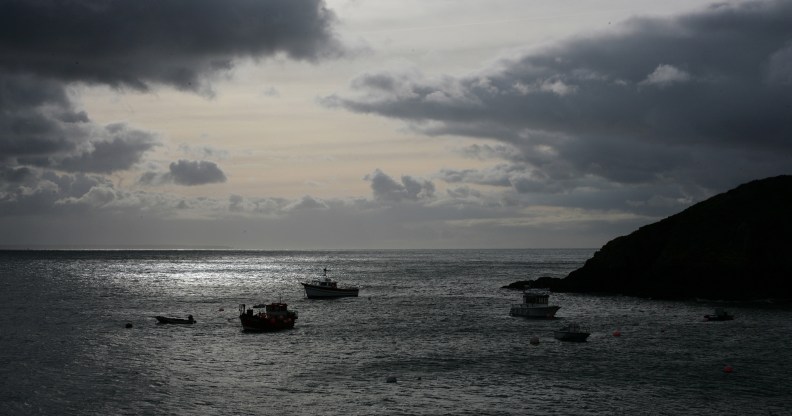 View out to sea from Creux Harbour on Sark, showing fishing boats in silhouette on a grey sea with a cloudy grey sky, 21st November 2008