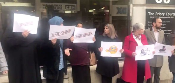 Protestors holding signs reading 'gag order'