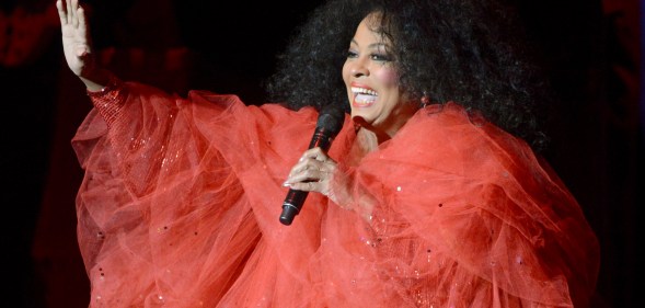 Diana Ross in a red dress performing on stage in concert.
