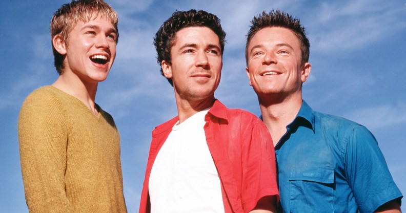 Nathan, Stuart and Vince from Queer as Folk, smiling against a blue sky