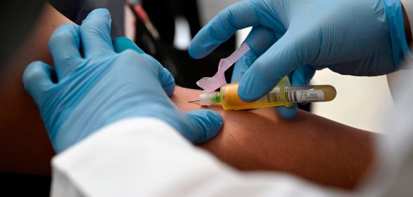 A technician extracts blood from a patient for an HIV test.
