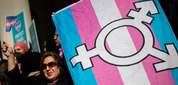 An LGBT+ activist holding the trans flag